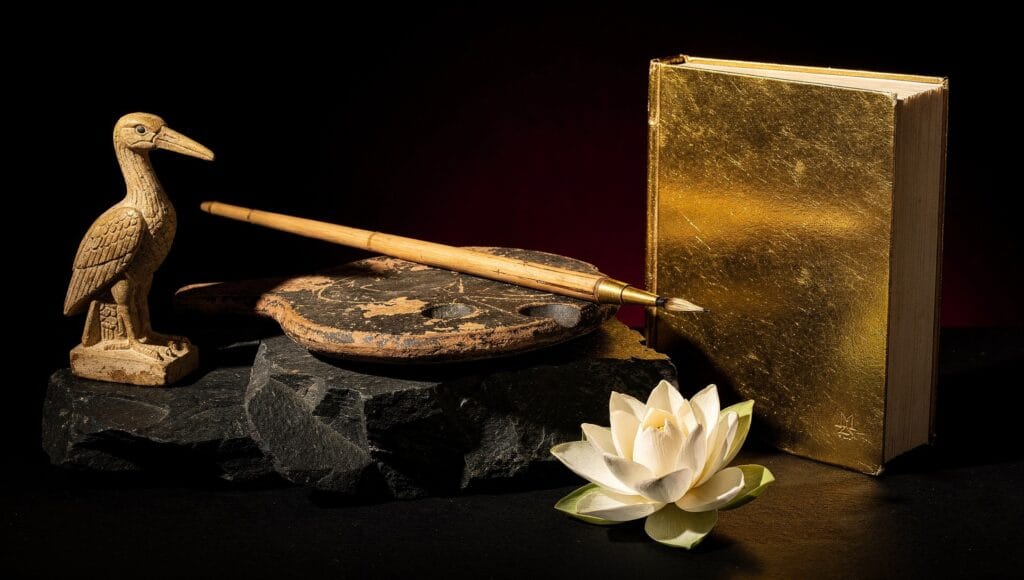 Cosmic records in world traditions: an ibis figure, a scribe palette and reed pen, a golden book and a lotus on black stone
